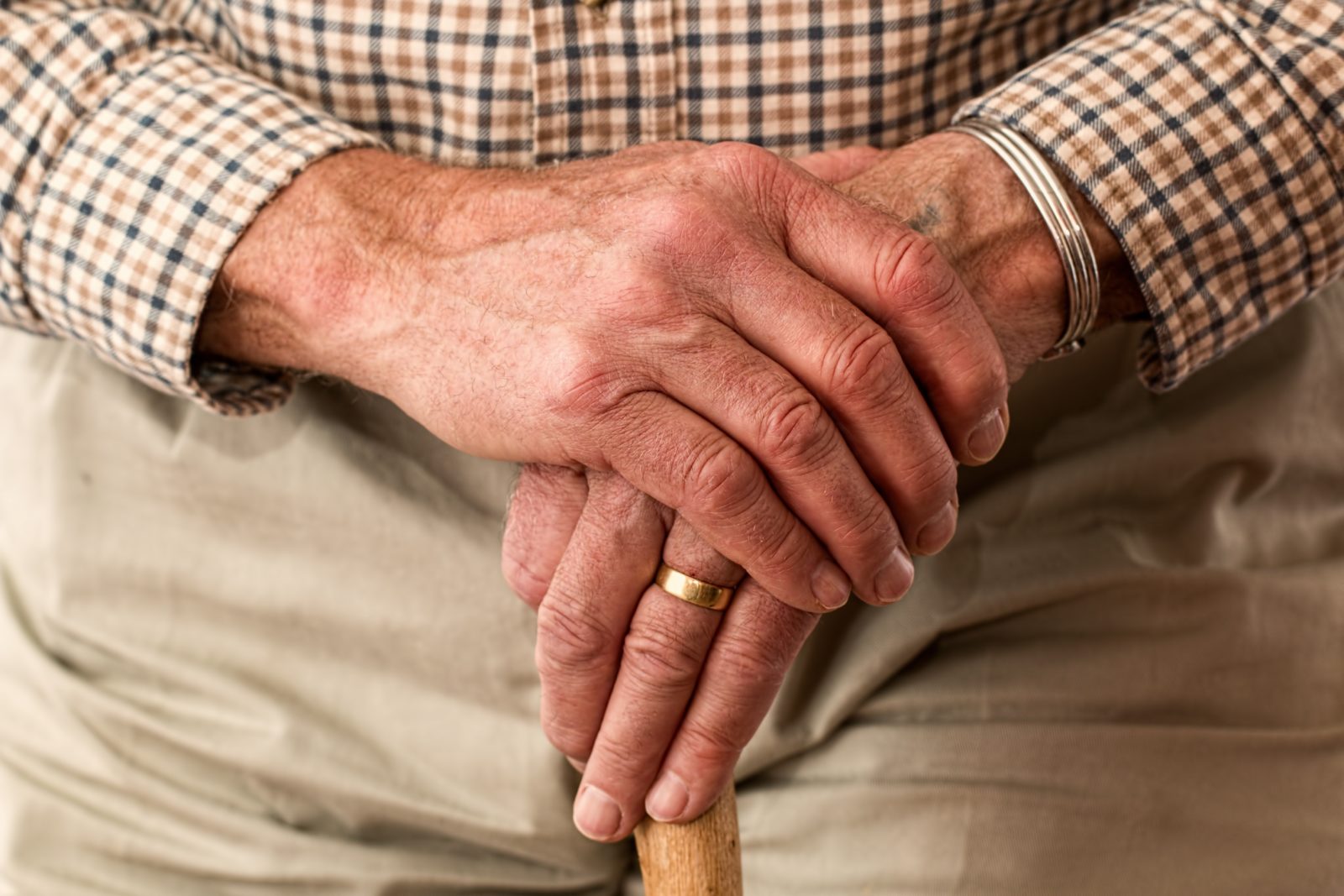 Elderly hands holding walking stick
